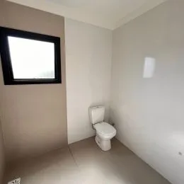 Banheiro simples com vaso sanitário e piso claro.