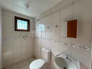 Foto de um banheiro com azulejos brancos e louças sanitárias.