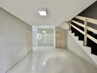 Hall de entrada com piso claro e escadaria.