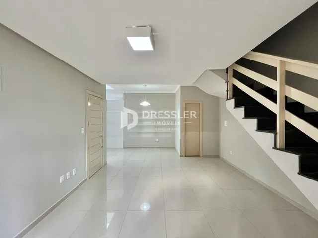 Hall de entrada com piso claro e escadaria.