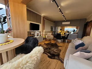 Sala de estar moderna com piso de madeira e sofá claro.