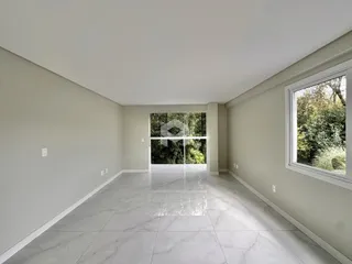 Vista de um corredor interno com piso de porcelanato claro e grande janela ao fundo.