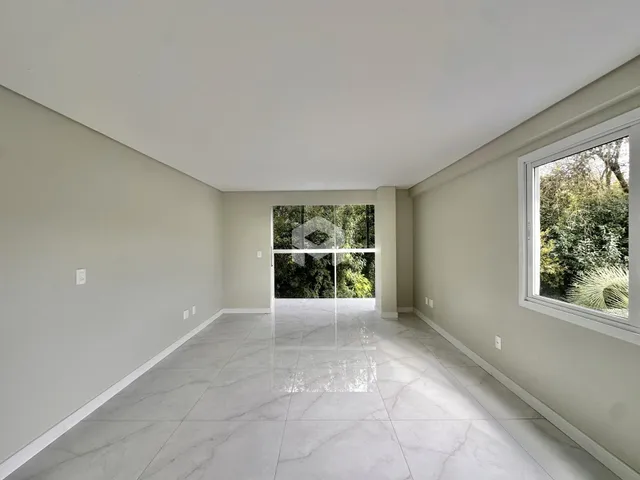 Vista de um corredor interno com piso de porcelanato claro e grande janela ao fundo.
