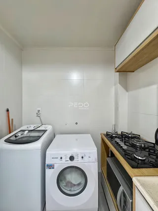 Foto de uma área de serviço com máquinas de lavar e cozinha.