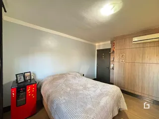 A foto mostra um quarto com cama e painel de madeira na parede.