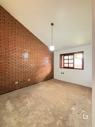 Interior com paredes de tijolo aparente e piso de concreto em uma residência.