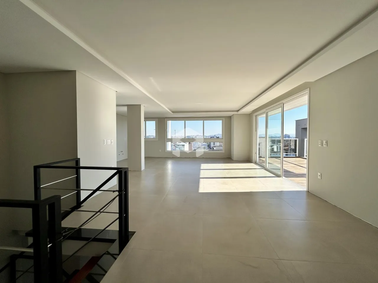 Ambiente interno de uma sala ampla com piso claro e porta de vidro.