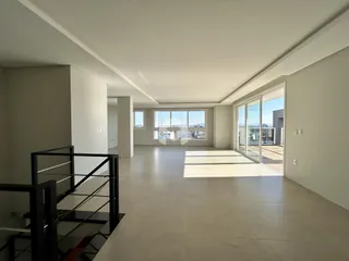 Ambiente interno de uma sala ampla com piso claro e porta de vidro.