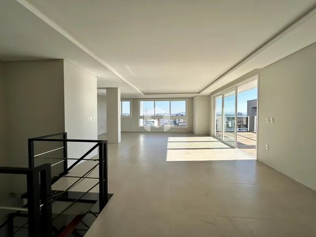 Ambiente interno de uma sala ampla com piso claro e porta de vidro.