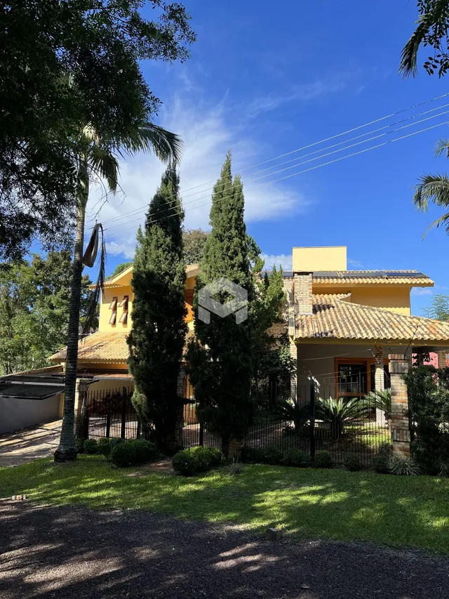 Fachada de uma residência em Lajeado, Brasil, cercada por árvores e gramado.