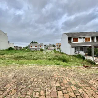 Vista externa de casas em Lajeado com área gramada e pavimento de tijolos.
