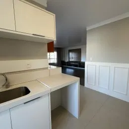 Vista de uma área de bancada e armários brancos em uma cozinha.