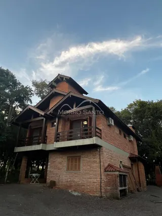 Fachada de uma casa de tijolos vermelhos com varanda no andar superior.