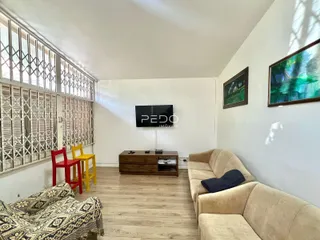 Sala de estar com piso de madeira e janelas com venezianas
