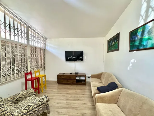 Sala de estar com piso de madeira e janelas com venezianas