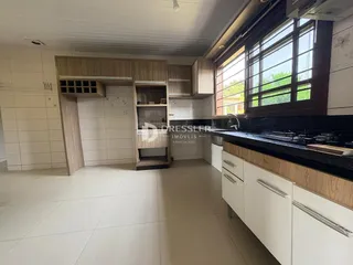 Vista interna de uma cozinha com armários de madeira e piso claro.
