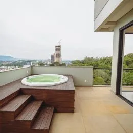 Uma área externa com um deck de madeira e uma banheira de hidromassagem com vista.