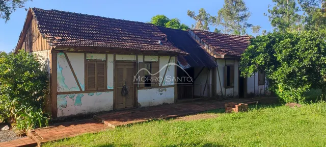 Foto da fachada de uma casa rústica com telhado de telhas e jardim gramado.