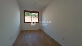 Vista interna de um cômodo com piso de madeira e janela.