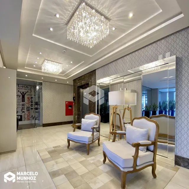 Sala de estar com teto alto e lustre de cristal refletido em espelhos.