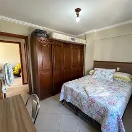 Quarto com cama e cabeceira de madeira em um imóvel.