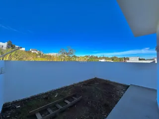 Parede branca de um imóvel com terra exposta no primeiro plano.