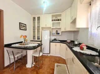 Foto de uma cozinha com armários brancos e bancadas escuras.