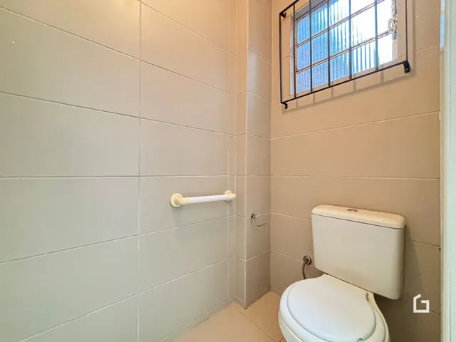 Foto de um banheiro com paredes revestidas de azulejos claros.