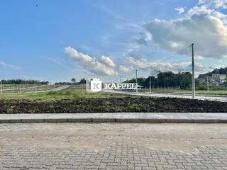 Vista externa de um campo aberto com vegetação e cerca.