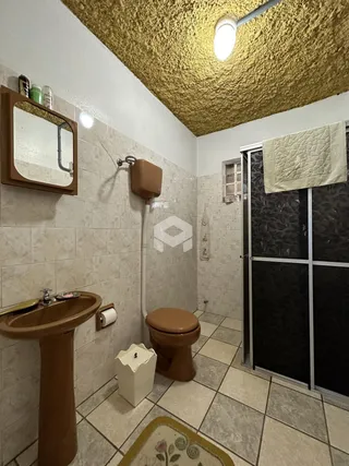 Foto interna de um banheiro com revestimento cerâmico e piso de azulejo.