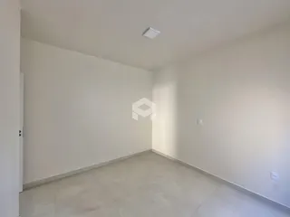 Vista interna de um cômodo com paredes brancas e piso de cerâmica.