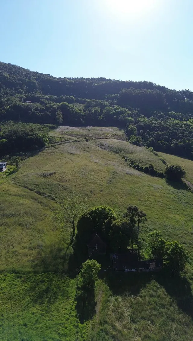 Vista aérea de uma propriedade com colinas verdes e vegetação.