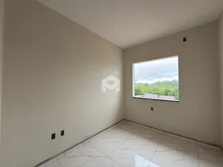 Vista interna de uma sala com parede clara e piso de porcelanato.