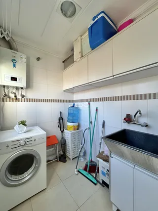 Foto da cozinha com armários brancos e piso de cerâmica.