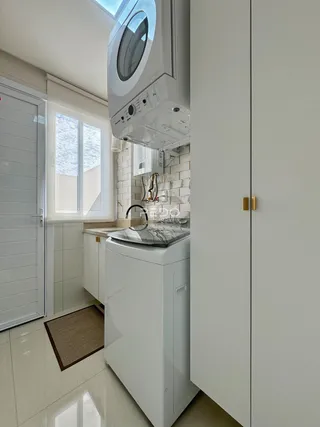 Uma cozinha moderna com armários brancos e revestimento de azulejos brancos.