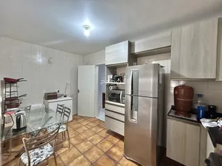 Foto de uma cozinha com armários e mesa de jantar em um imóvel no Brasil.