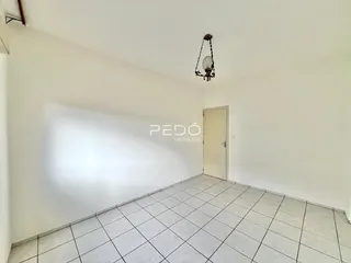 Uma sala interna com paredes brancas e piso de cerâmica clara.