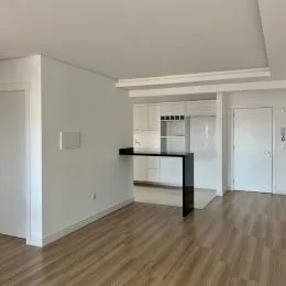 Vista interna de uma área com piso de madeira e armários de cozinha.