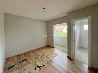 Interior de uma sala com piso de madeira e paredes cinzas.