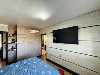 Quarto com cabeceira e televisão em ambiente moderno.