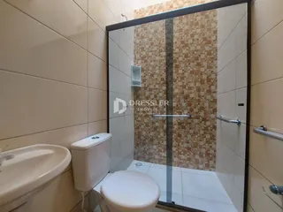 Interior de um banheiro com azulejos brancos e detalhes em tons terrosos.