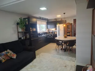 Ambiente interno de sala de estar com cozinha e mesa de jantar em Lajeado.