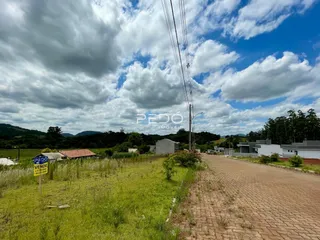 Vista externa de uma propriedade rural com campo gramado e estrada de terra.