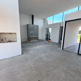 Foto de um espaço interno amplo com piso de concreto e lareira em uma residência.