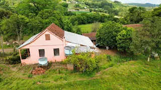 Fachada de uma casa antiga com telhado de metal em uma área rural.
