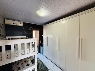 Quarto com armários embutidos e cabeceira de madeira branca.
