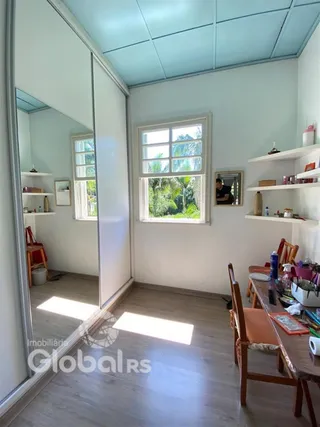 Vista interna de uma sala com piso de madeira e janelas.