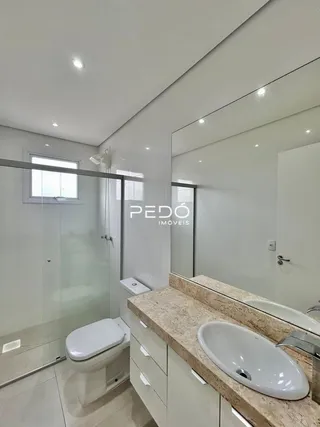 Banheiro moderno com box de vidro e bancada de granito.