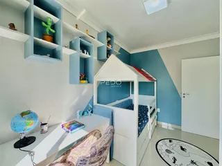 Quarto com cama de solteiro e estantes em um ambiente claro.