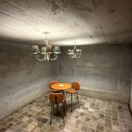 Foto de um ambiente interno com paredes de concreto aparente e piso de ladrilhos.